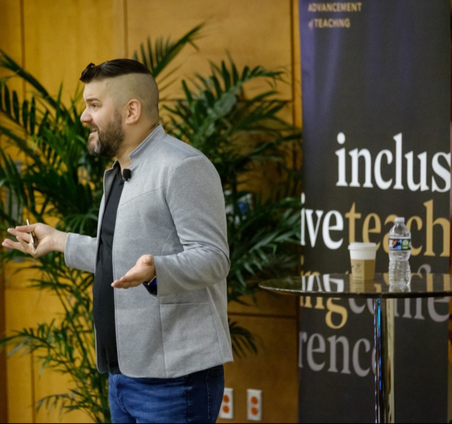Will Cox presenting in front of a fern and inclusive teaching conference banner