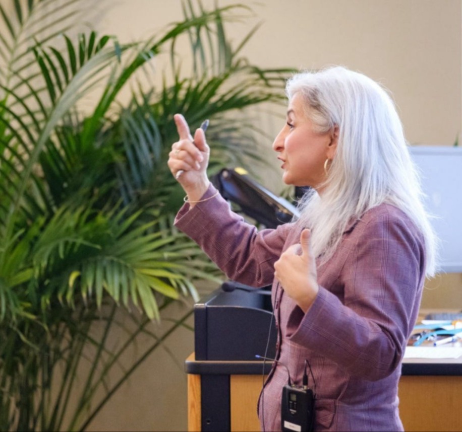 Pamela Barnett presenting with a fern and computer behind her.